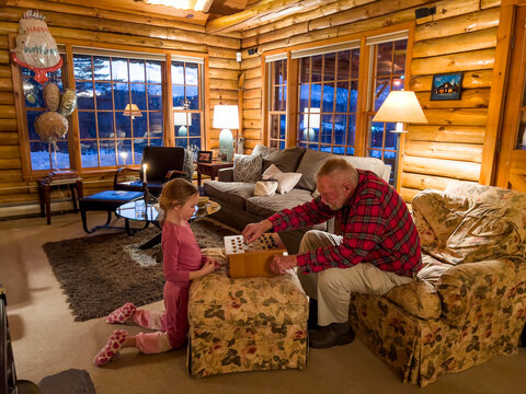Family together playing checker board game in cozy log cabin 