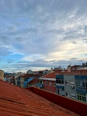 sunset view from the rooftop, city view, roofs of the buildings, evening cloudy sky