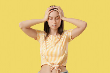 Tired young woman suffering from headache on yellow background - obrazy, fototapety, plakaty