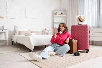 Female tourist with passport and suitcases in hotel room