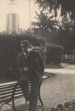 1969. Man in black suit posing for a portrait and smoking a cigarette