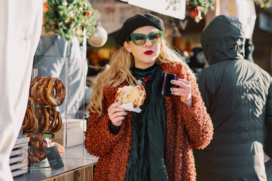 Fashionable blond woman with a pretzel and a hot drink