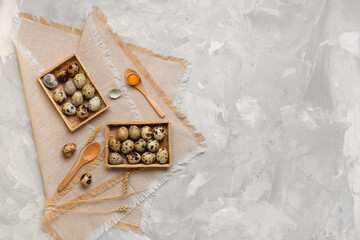 Wooden boxes with fresh quail eggs on grey background