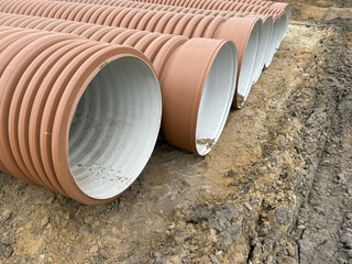 Corrugated Double-Walled Polypropylene Pipes Lined Up at a Construction Site During Daytime....