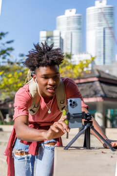 Teenage boy filming video on mobile phone in university campus