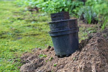 Empty black plastic plant pots on a heap of garden soil after planting in the backyard or park, gardening concept, copy space, selected focus