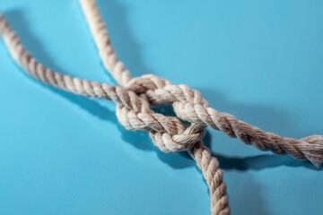 Knot of two ropes on a blue background, concept for teamwork, business and togetherness, copy space, selected focus - 777745494