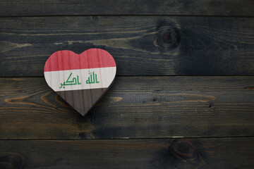 wooden heart with national flag of iraq on the wooden background.