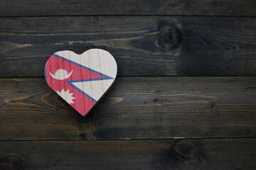 wooden heart with national flag of nepal on the wooden background.