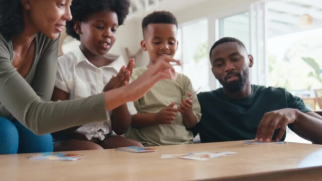 Family indoors at home having fun playing game of cards together - shot in slow motion