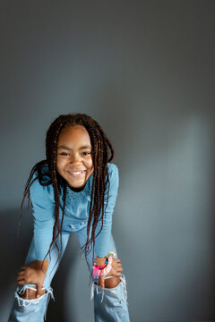Portrait of 11 year old girl smiling to camera over grey background