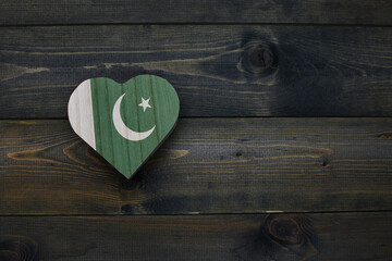 wooden heart with national flag of pakistan on the wooden background.