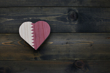 wooden heart with national flag of qatar on the wooden background.