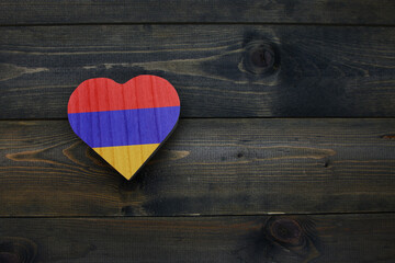 wooden heart with national flag of armenia on the wooden background.