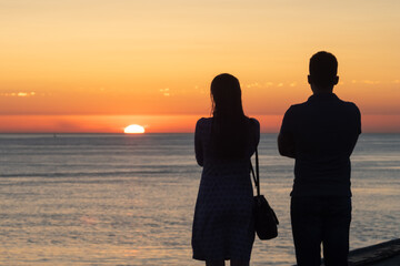 A couple watching sunset at an ocean