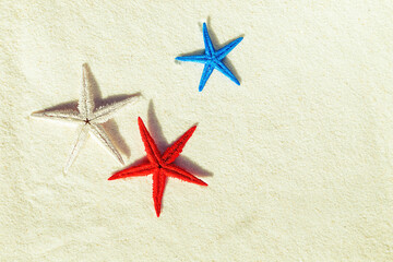 Colored starfish on white fine sand.