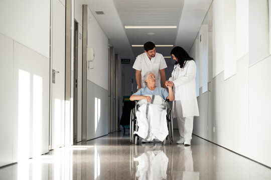 Nurse pushing patient in wheelchair at corridor