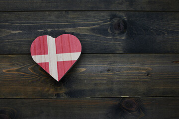 wooden heart with national flag of denmark on the wooden background.