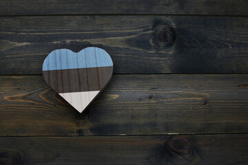 wooden heart with national flag of estonia on the wooden background.