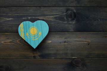 wooden heart with national flag of kazakhstan on the wooden background.