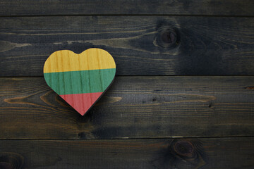 wooden heart with national flag of lithuania on the wooden background.