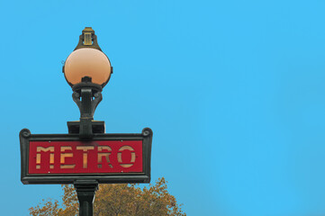 Sign at metro station in Paris with treetop in the back and clear blue sky. Selective focus