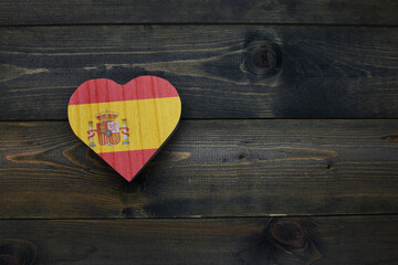 wooden heart with national flag of spain on the wooden background.