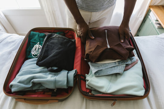 A man packing a pullower in a suitcase