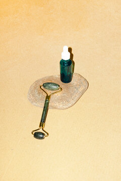 Green jade roller and skincare blue serum with hard direct flashlight