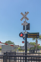 Vertical view of railroad track crossing with light, gate, northbound and southbound signs and copy space