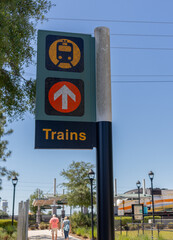 Obraz premium Green, yellow and orange directional sign with arrow and train icon leading passengers to platform