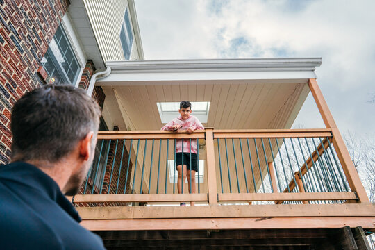 Dad looking up at son on balcony. 