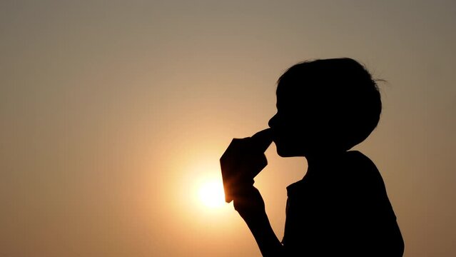 An Asian boy is playing with a paper plane in his hand at sunset. Concept of a boy's dream of becoming a pilot.