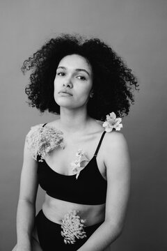 Black and white female studio portrait with flowers on body.