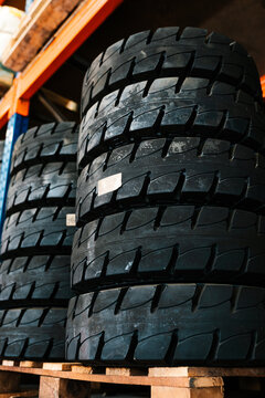 Black truck tires stack up on wooden board in workshop