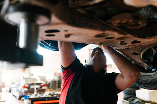 Serious male mechanic repairing car in workshop