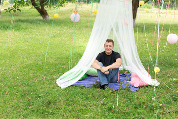 location in nature. canopy canopy on a tree with ribbon lanterns, a man under the canopy © Svetlana