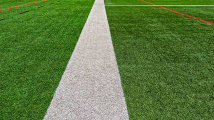 Football Field Turf. Bright green turf football field surface with white sidelines and yard line markings. Overhead view.