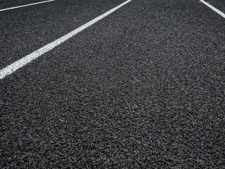 Track and Field Running Lanes. Overhead view of a rubber black running track surface with white lane lines. Surface level view of the textured rubber black surface.