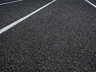 Fototapeta premium Track and Field Running Lanes. Overhead view of a rubber black running track surface with white lane lines. Surface level view of the textured rubber black surface.