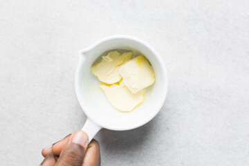 pieces of butter in a white ceramic measuring cup, organic butter in a white measuring cup