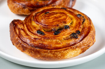 Breakfast in bakery with fresh baked coffee buns sweet pastry with raisins, morning food close up