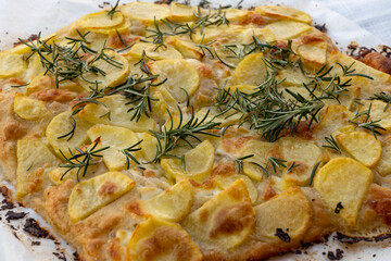 Fresh baked focaccia or pala romana pizza with potato vegetables and rosemary in bakery in Parma,...