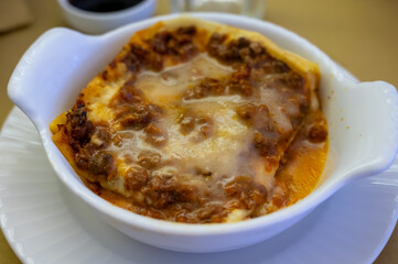Traditional first course for lunch or dinner in Italy, lasagne Bolognese with beef meat and bechamel sauce served in Italian restaurant, Milan, Italy