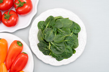 Fresh tomatoes, paprika, green Spinach leaves, diet and health concept, weight loss, spinach on ceramic plate, copy space