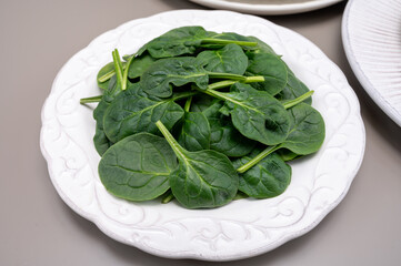 Fresh green baby Spinach leaves, diet and health concept, weight loss, spinach on ceramic plate, copy space