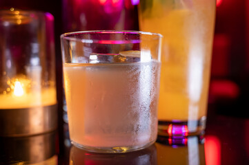 Whiskey and rum colorful cocktails served with ice cubes on black table in dark cocktail bar in Italy