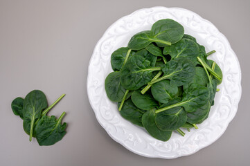 Fresh green baby Spinach leaves, diet and health concept, weight loss, spinach on ceramic plate, copy space