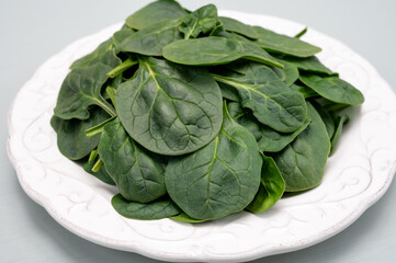 Fresh green baby Spinach leaves, diet and health concept, weight loss, spinach on ceramic plate, copy space
