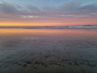 Sunset on Famara Beach, Lanzarote, casts a mesmerizing palette of colors across the sky, blending hues of orange, pink, and purple against the backdrop of the Atlantic Ocean waves.